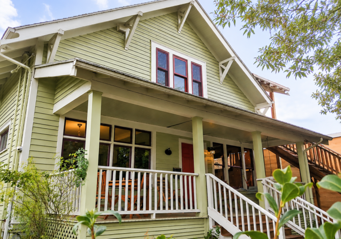 A green house with white trim and a porch